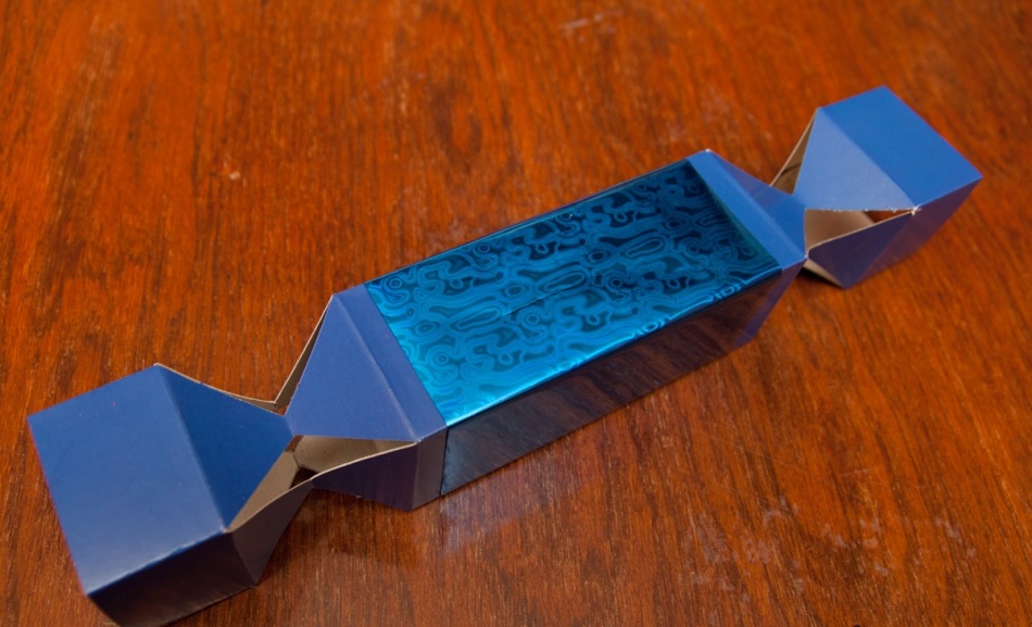 Приклеивание оберточной бумаги к картонной основе упаковки для конфет