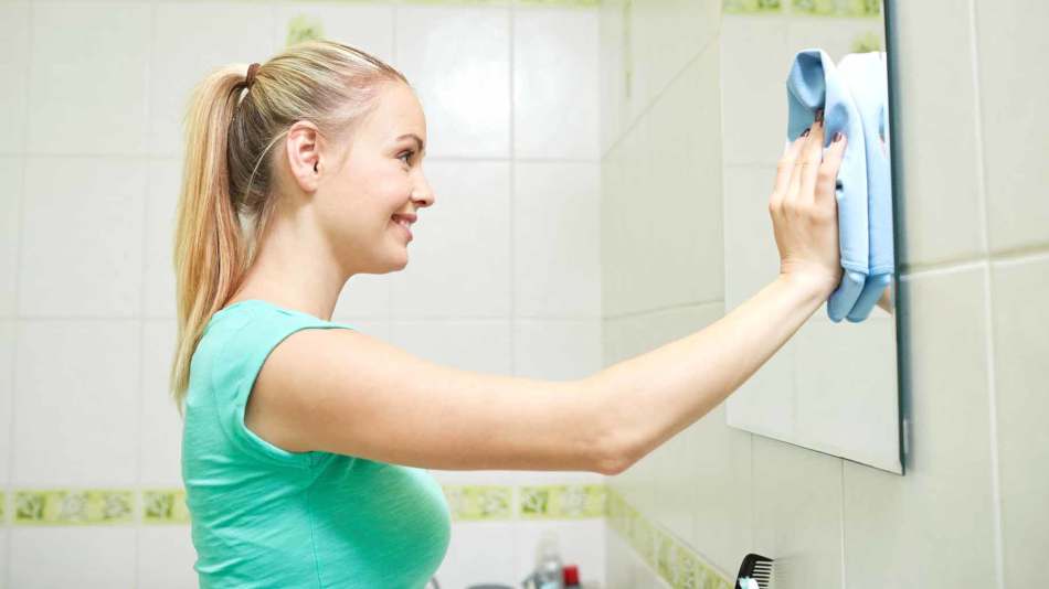 Девушка моет зеркало в ванной