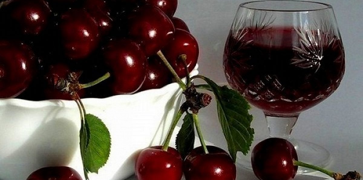 Бокал смородиново-вишневого домашнего вина и пиала с вишней