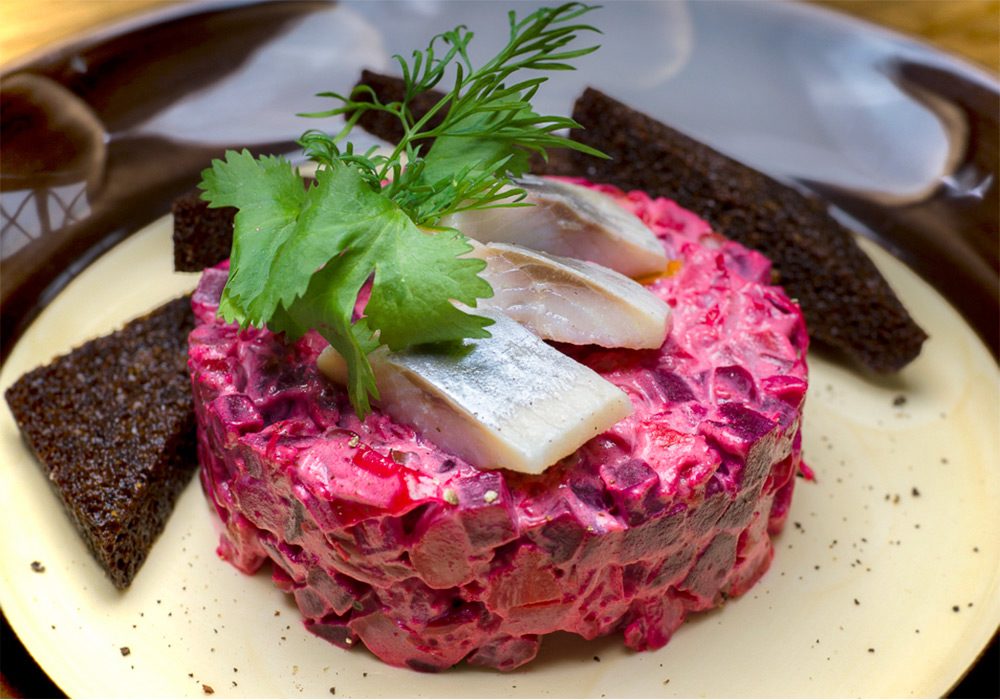 Порция ароматного винегрета с майонезом с несколькими кусочками селедки