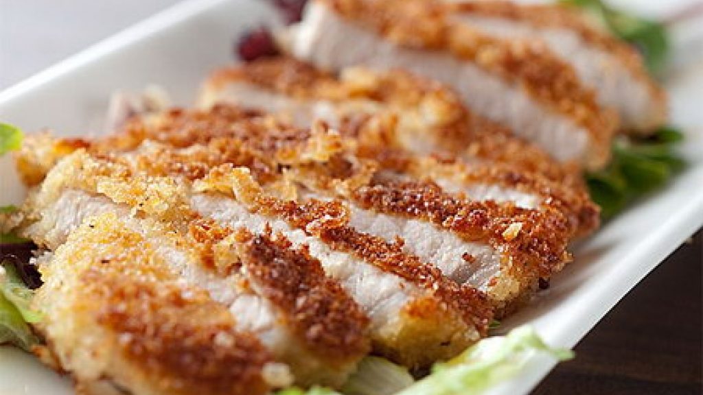 Свинная отбивная порезана на куски в тарелке