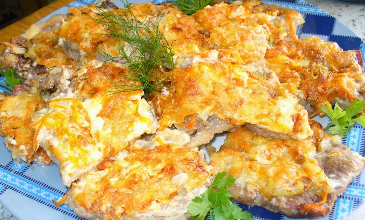 Горка готовых отбивных из свинины, приготовленных с морковью и луком