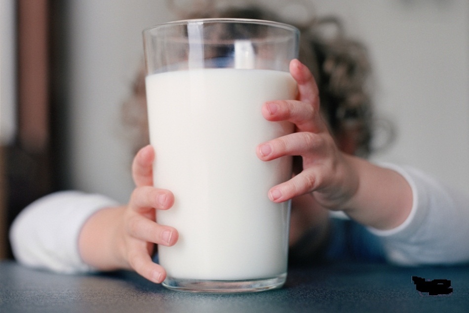 L'enfant tient un verre de lait bouilli avec ses mains