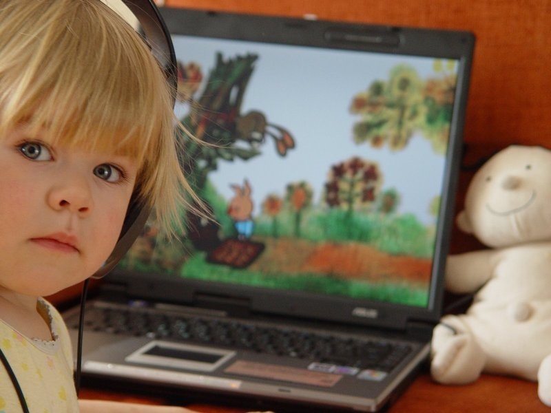Девочка смотрит мультик на ноутбуке