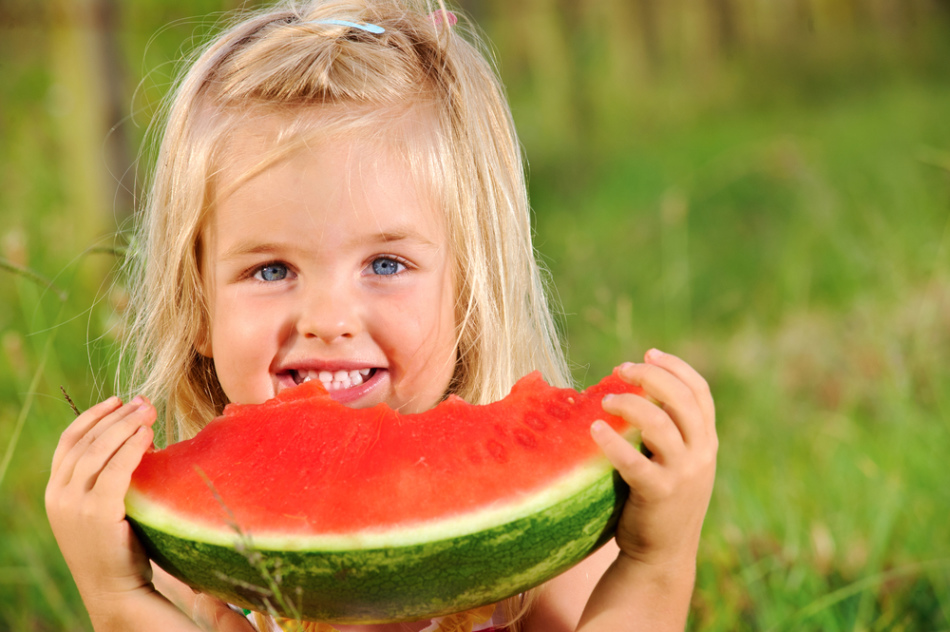 Gadis kecil makan sepotong semangka yang dicuci