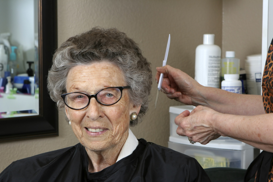 Une femme âgée sur une chaise dans un salon avant de teindre ses cheveux gris