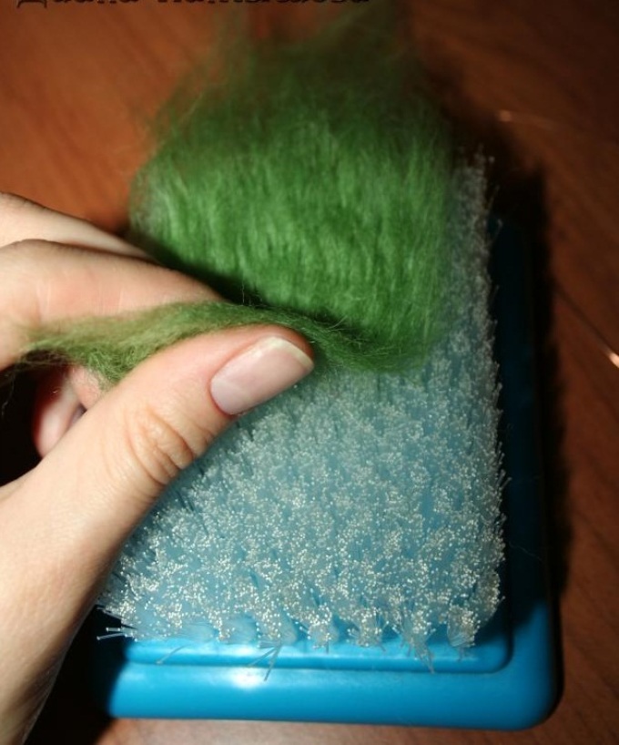 A strand of green wool during felting is processed on both sides