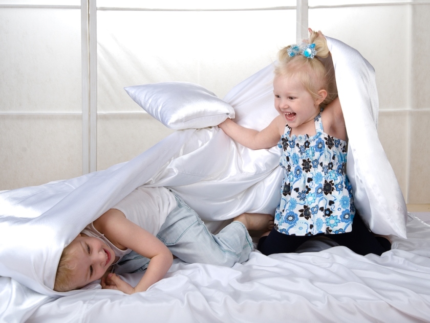 Дети дерутся в кровати подушками