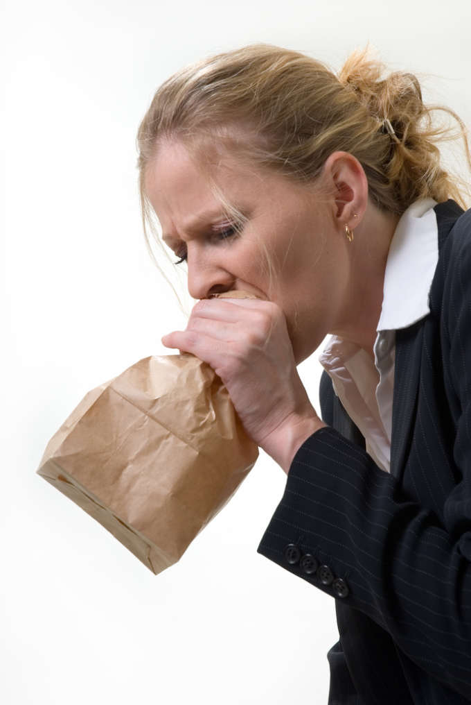 A woman breathes in a paper bag