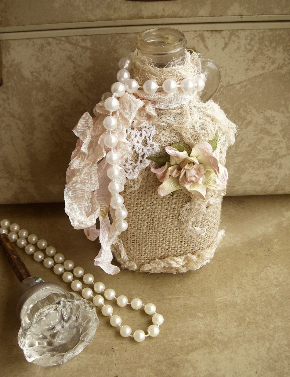 A bottle of decoupage made of fabric, beads and flowers