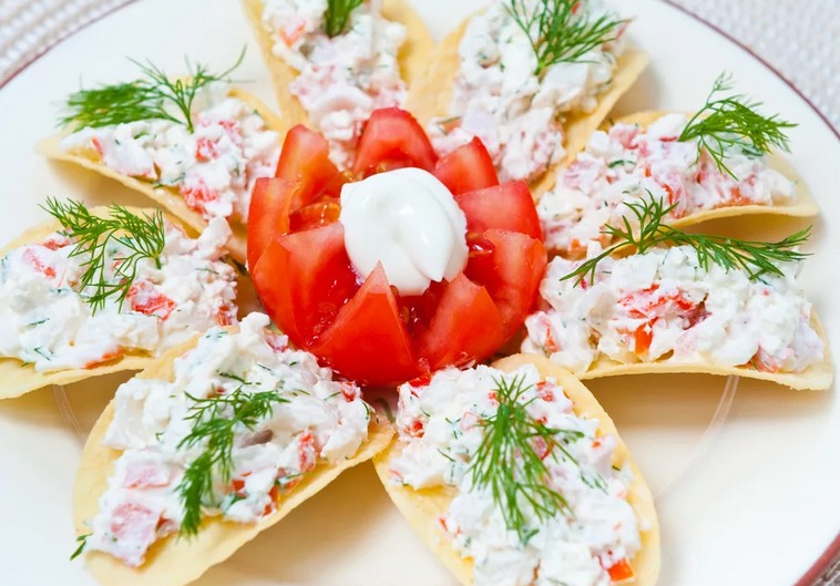 A delicious cold appetizer on the chips of Prungls on a festive table with crab sticks