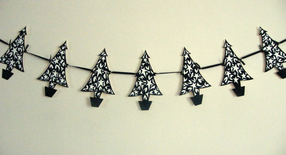 Bereites Papiergirlande von geschnittenen Weihnachtsbäumen an der Wand