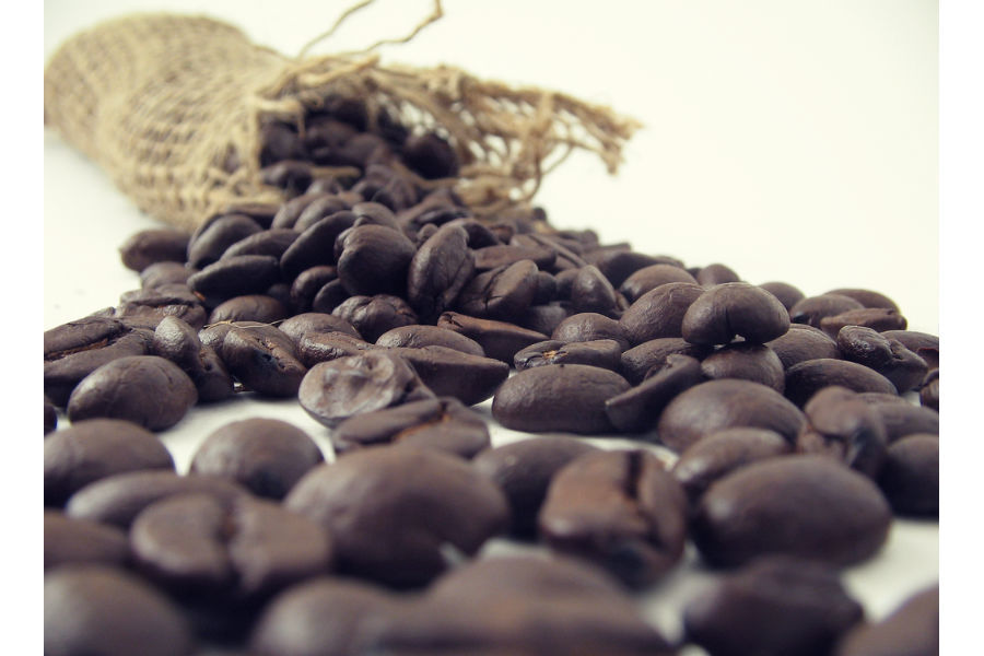 Naravna kavna zrna so raztresena po mizi, preden se zmelje za barvanje sivih las