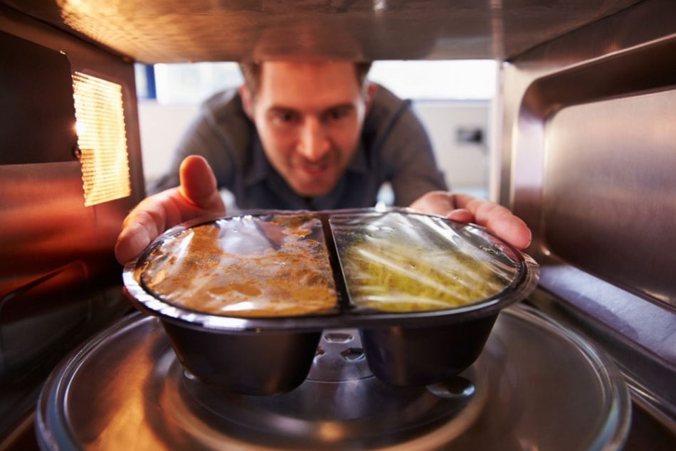 Moški ogreje hrano v mikrovalovni pečici