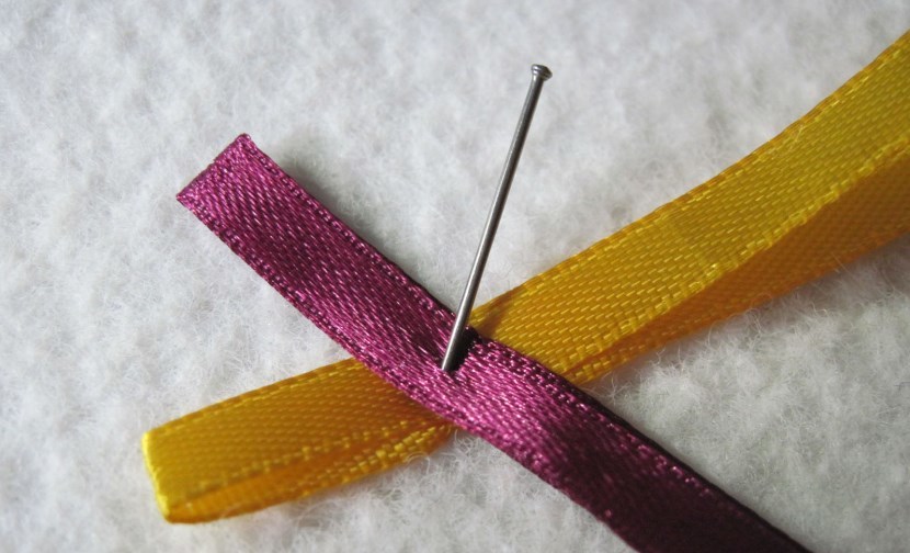 Fixation of tapes with a pin during the weaving process of the bookmark