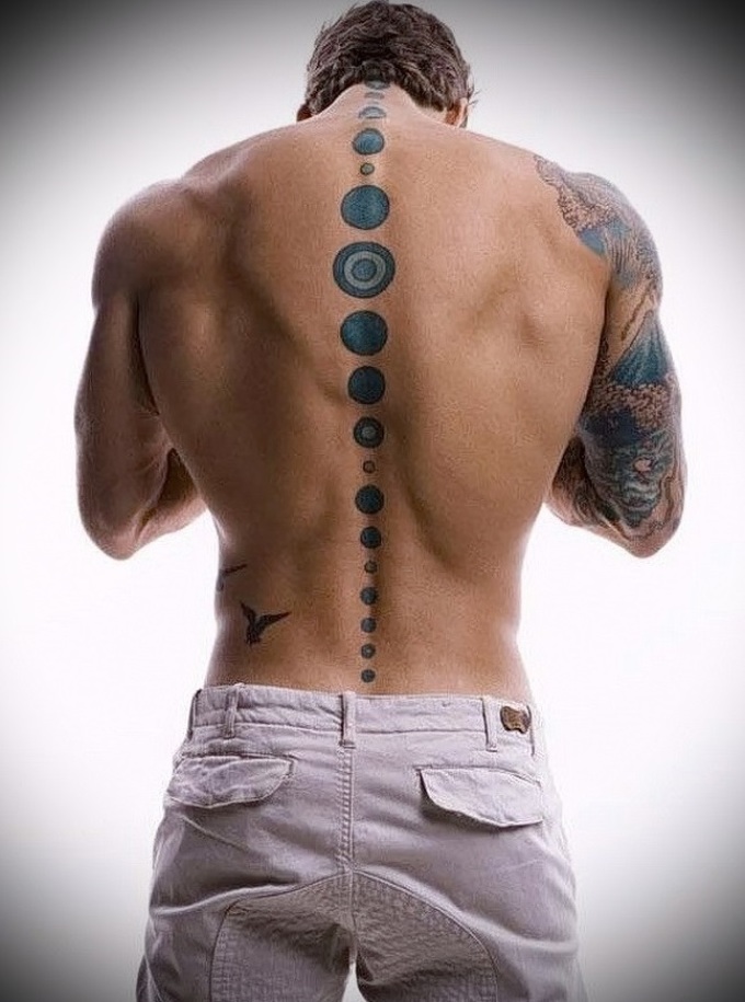 Татуировка-круги на мужском позвоночнике.