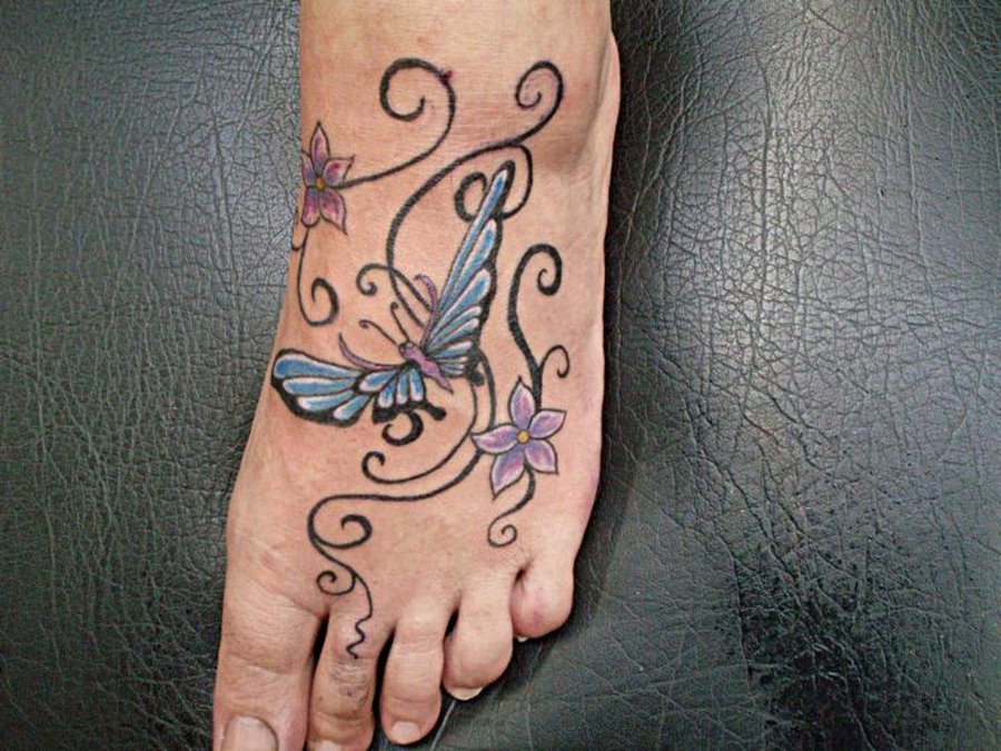 Tetoválás összefonódó minták formájában, virágokkal a női lábnál