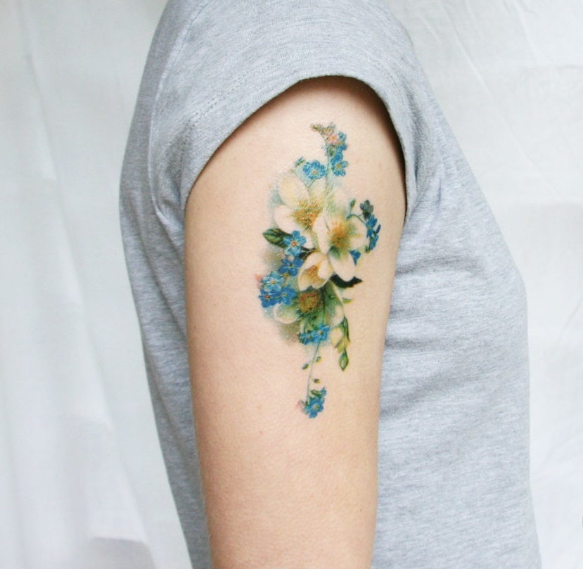 Finom tetoválás vadvirágok formájában a vállon