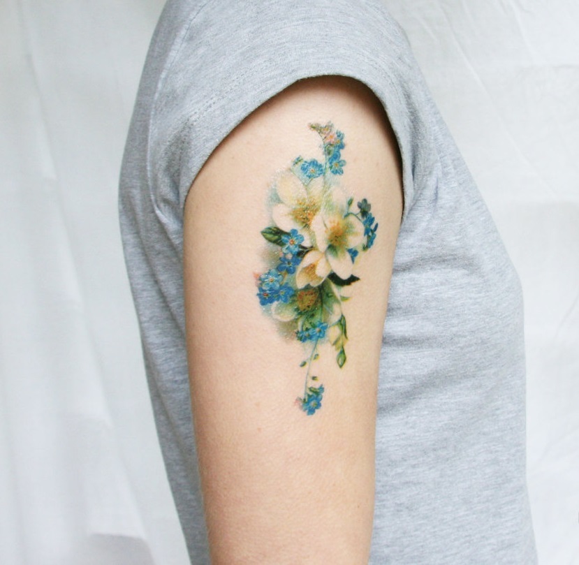 Zartes Tattoo in Form von Wildblumen auf der Schulter