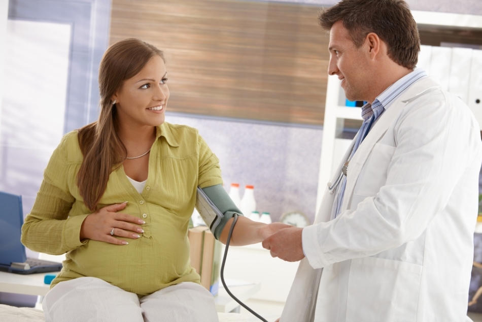 Zdravnik meri pritisk pri nosečnici, da razume prisotnost hipertenzije