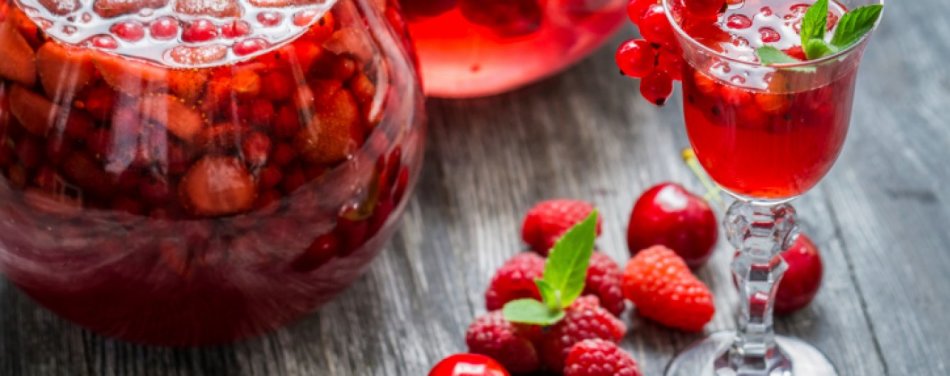 Anggur kismis dan raspberry dalam wadah kaca di atas meja