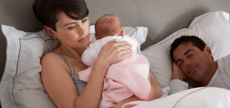 Fáradt fiatal anya a karjában tartja a babát