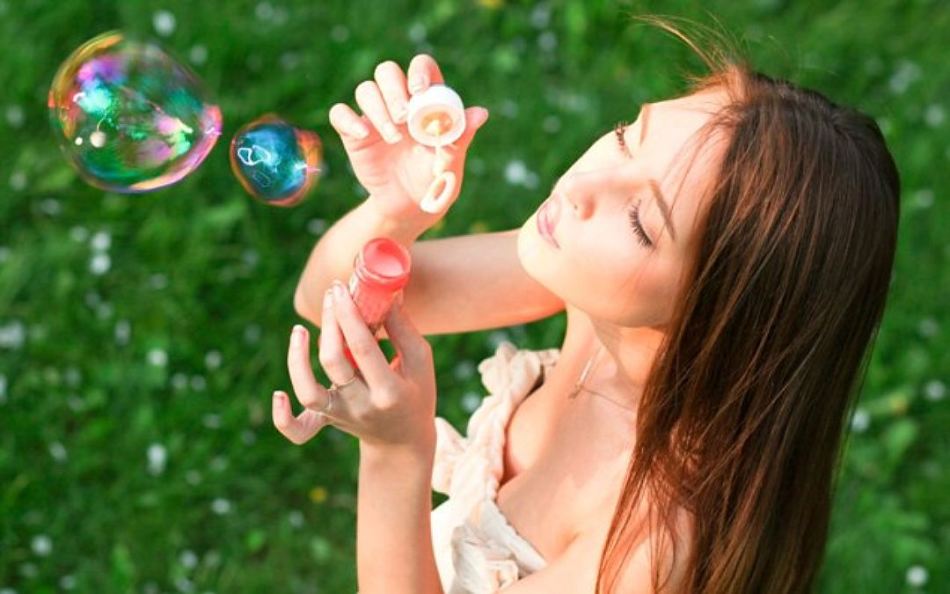 Девушка дует ароматные мыльные пузыри, изготовленные дома из детского шампуня
