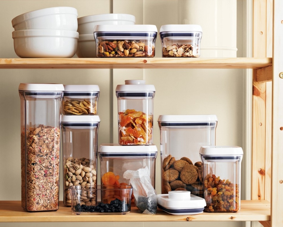 Different dried fruits are fed in glass containers for storage on the shelves of the kitchen