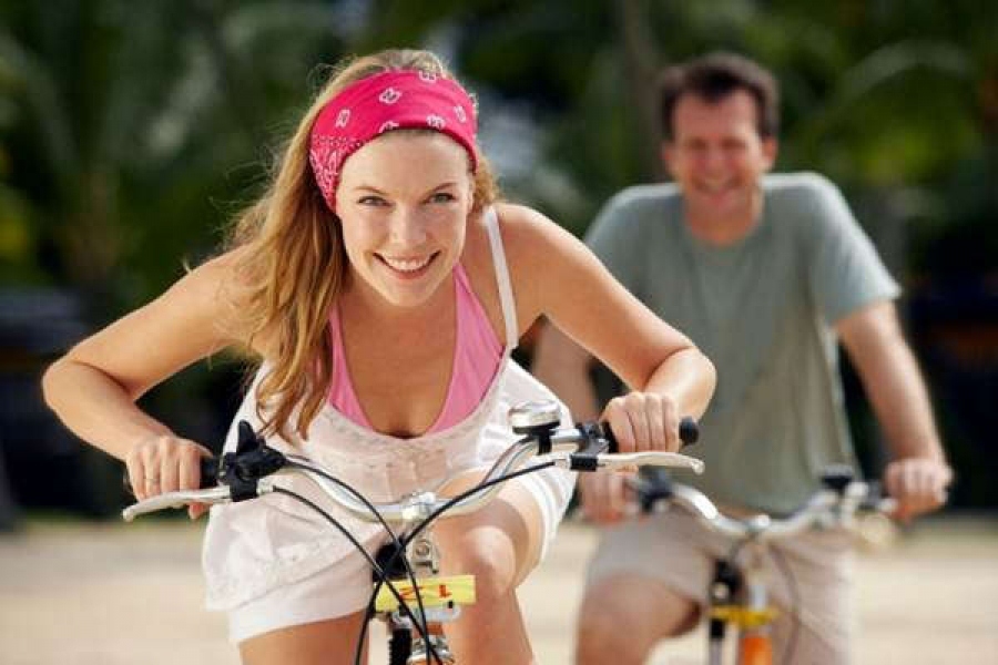 Tersenyum pirang bergerak di atas sepeda dan tidak merasakan sakit di lutut