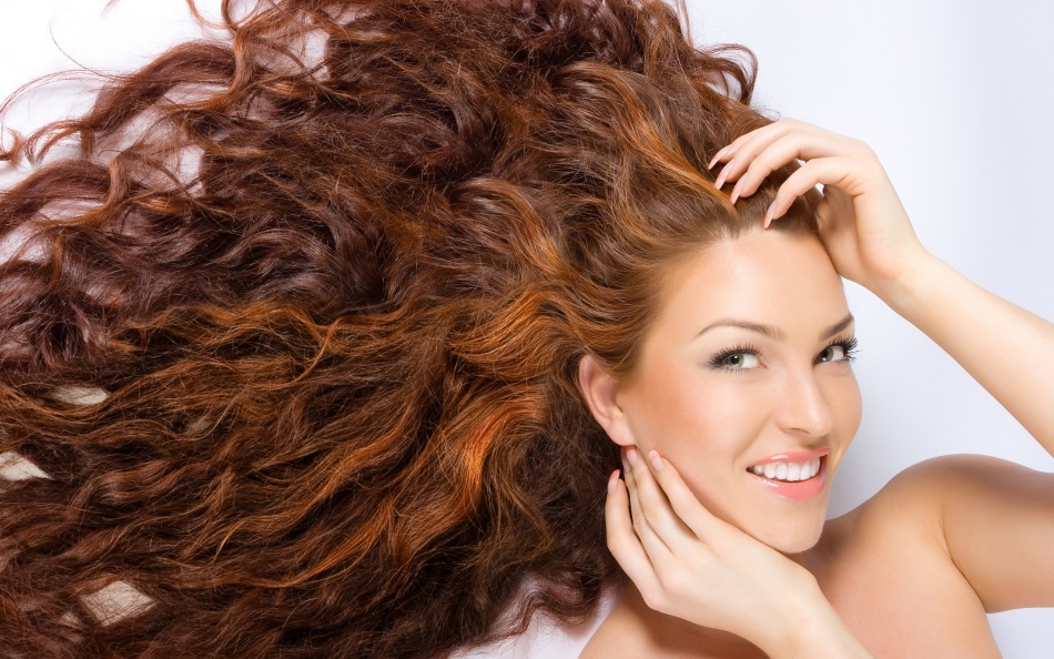 Smiling girl with long reddish hair after coloring henna