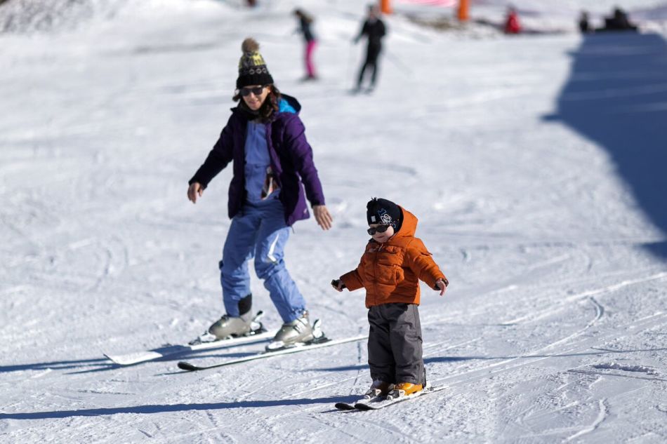 Мама и малыш катаются на лыжах классического хода без лыжных палок на грнолыжном курорте