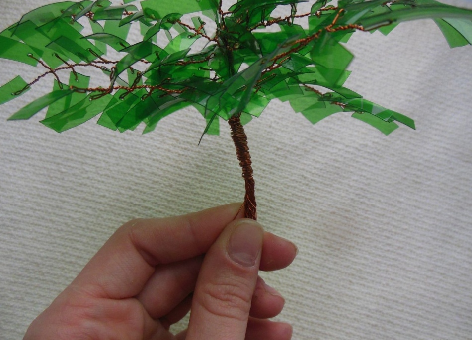 Menenun cabang ke dalam tong palem-bonsi dari botol plastik