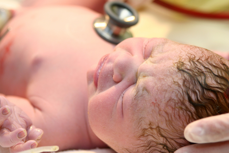 Доктор осматривает новоррожденного малыша для выставления оценок по апгар