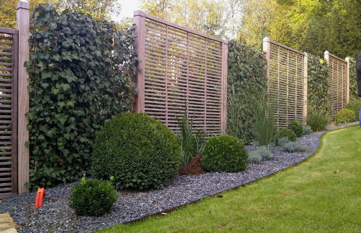 Комбинированный забор с сеткой-рабицы, с красивыми высаженными растениями вдоль ограды