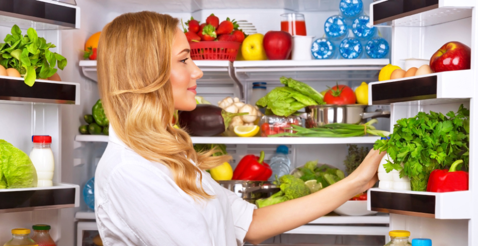 Девушка выбирает продукты в большом холодильнике