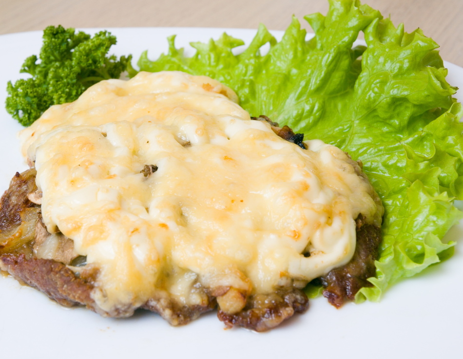 Carne de cerdo con champiñones, ensalada debajo del queso