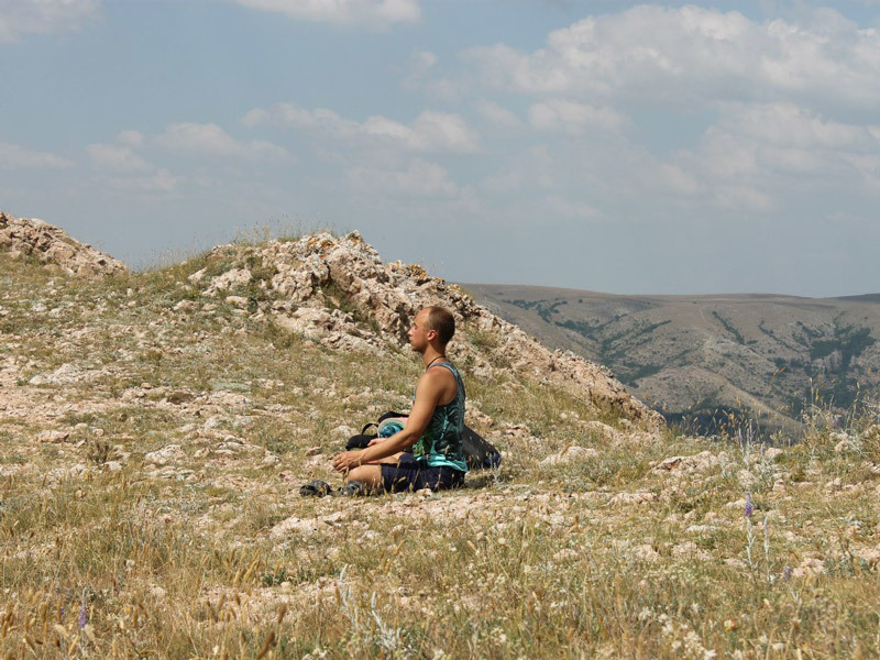 Мужчина медитирует в месте силы в горах