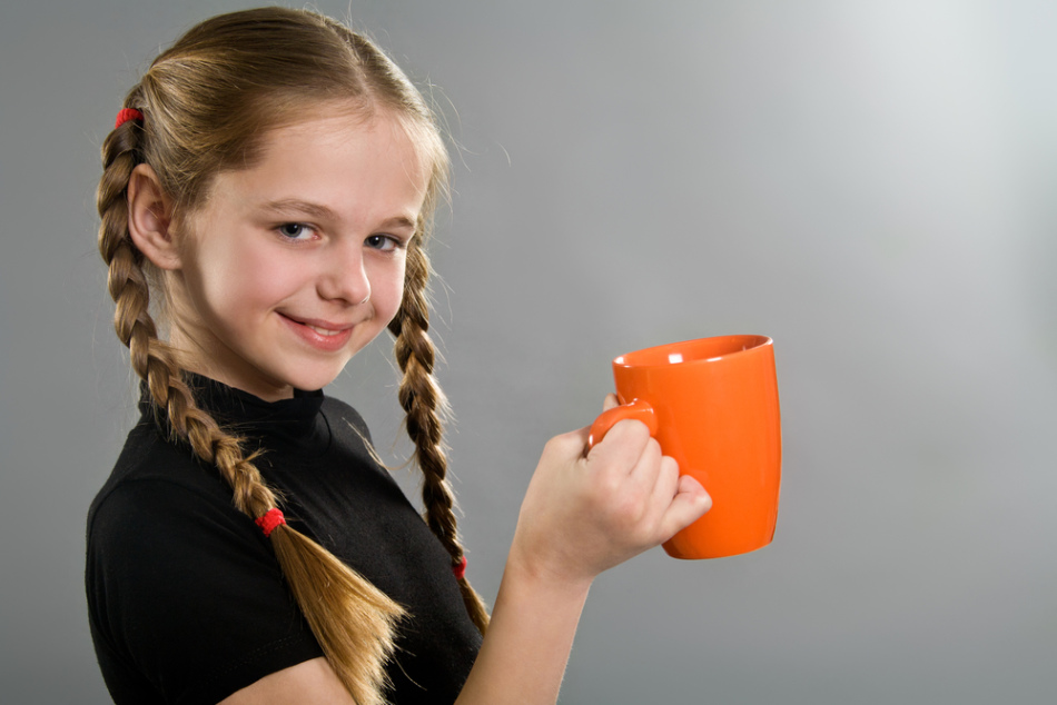 Seorang gadis remaja memegang secangkir kakao lezat di tangannya