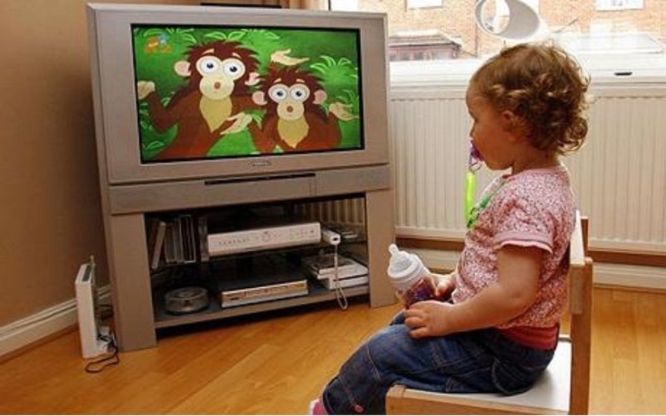 Маленькая девочка смотрит мультики по телевизору