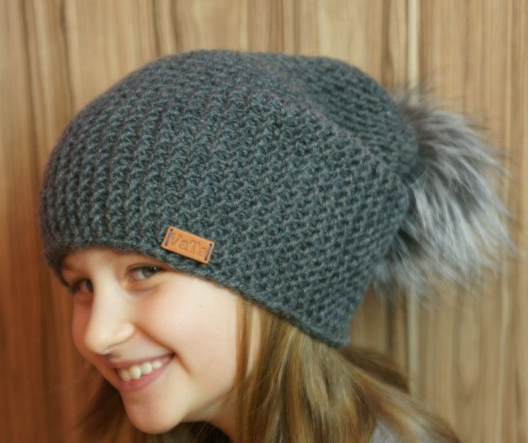 La fille a un chapeau Beino à la mode gris connecté par des aiguilles à tricotage
