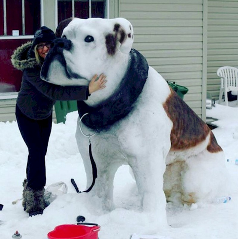 Grande sculpture de neige d'un chien avec une fillette