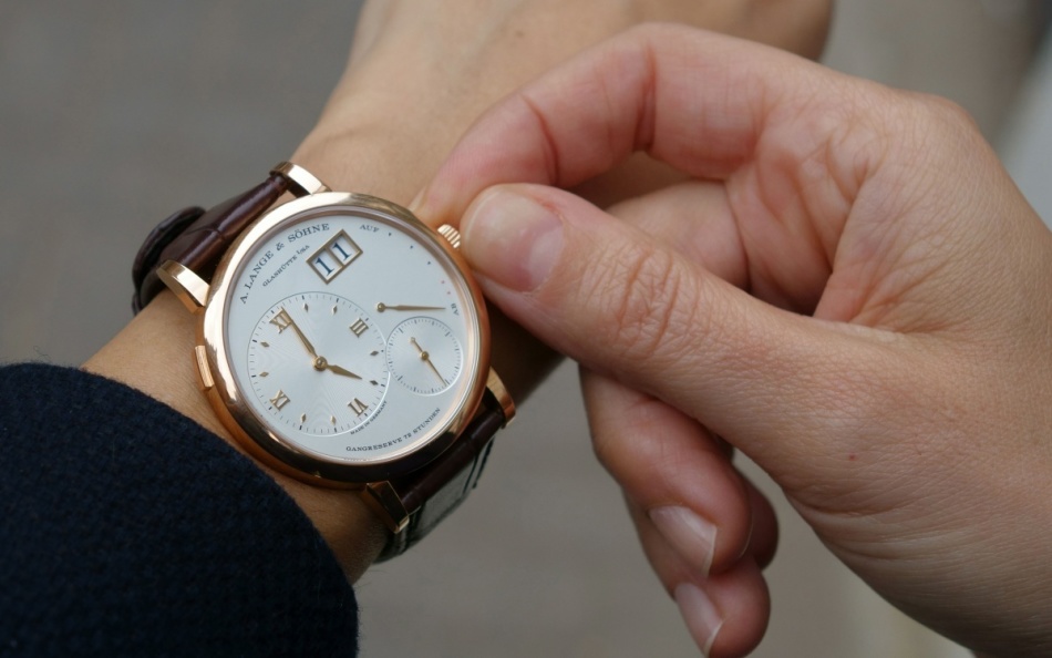 Ένας άντρας με ευχαρίστηση φοράει ένα δώρο - ένα ρολόι στο χέρι του