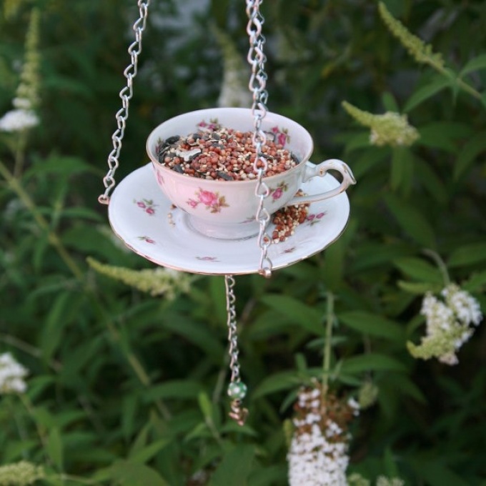 A cup glued to a saucer suspended on a tree is a great detail of the garden interior and a feeder at the same time