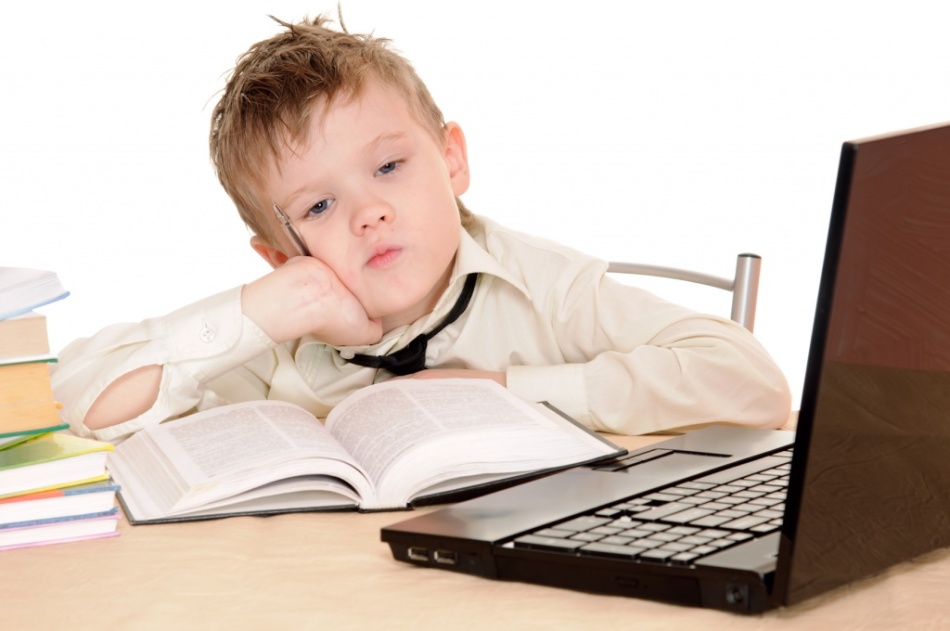 Мальчик задумался над открытыми книгой и ноутбуком о случаях написания слова "неактуально" слитно