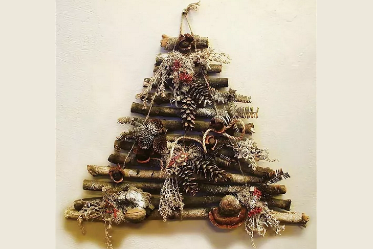Πρωτότυπο χριστουγεννιάτικο δέντρο στον τοίχο των μπαστούνια και τους κώνους με τα χέρια σας