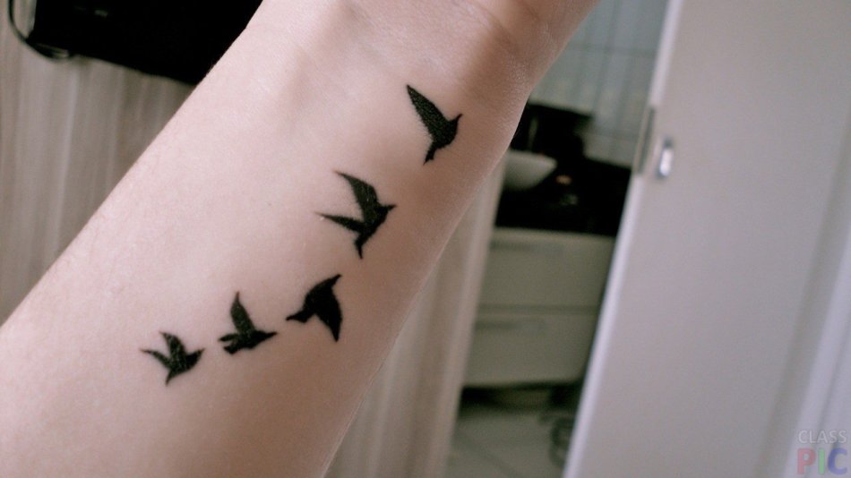 Tattoo in the form of flying birds on the wrist