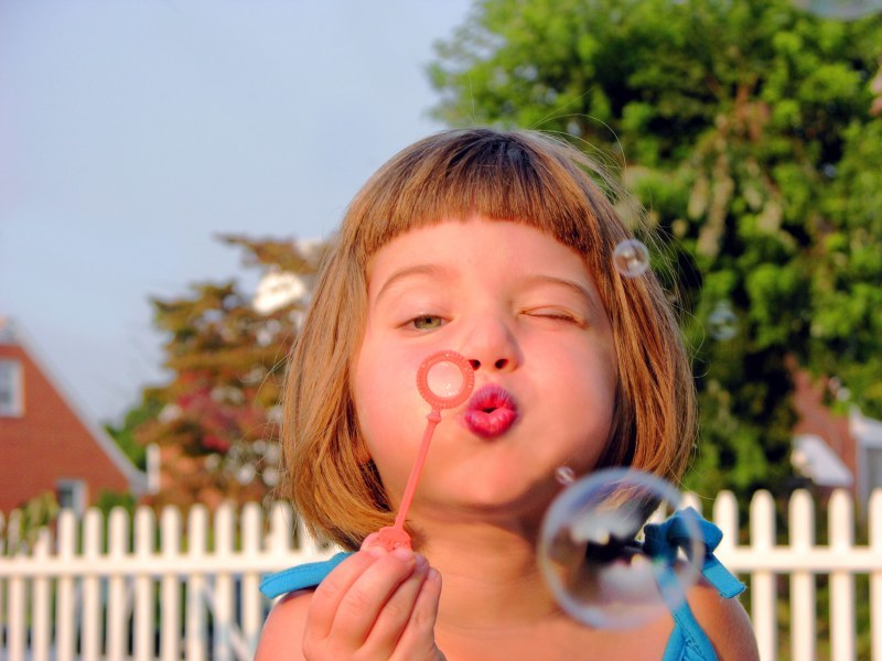 Девочка выдувает мыльные пузыри из домашнего раствора