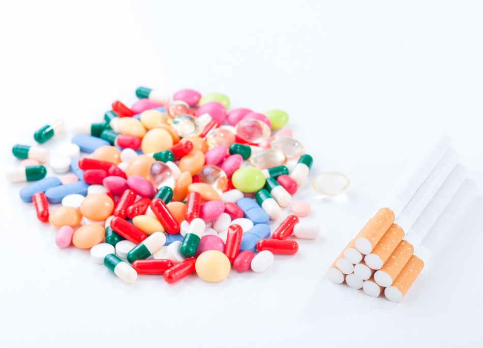 Különböző tabletták és antidepresszánsok kapszuláinak hegye a dohányzás megtagadása egy cigaretta halom mellett