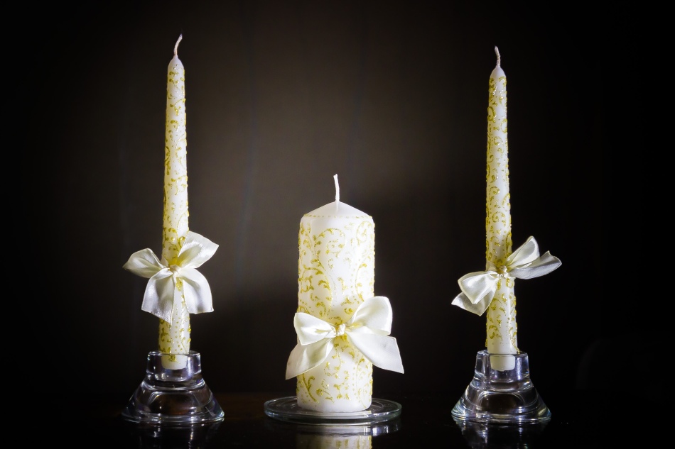 Изящные золотые узоры и простые белые банты на свечах