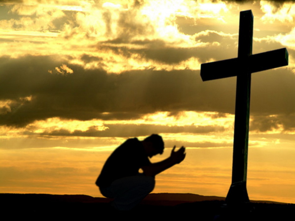 A man prays at the cross at dawn